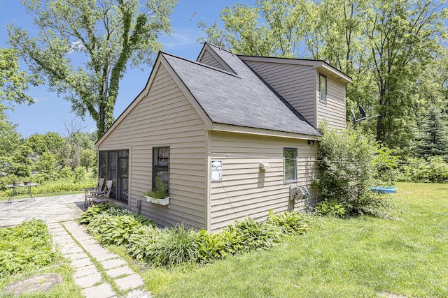 view of side of property featuring a patio and a lawn