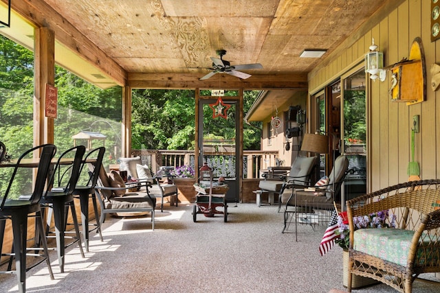 sunroom / solarium with plenty of natural light, ceiling fan, and wood ceiling