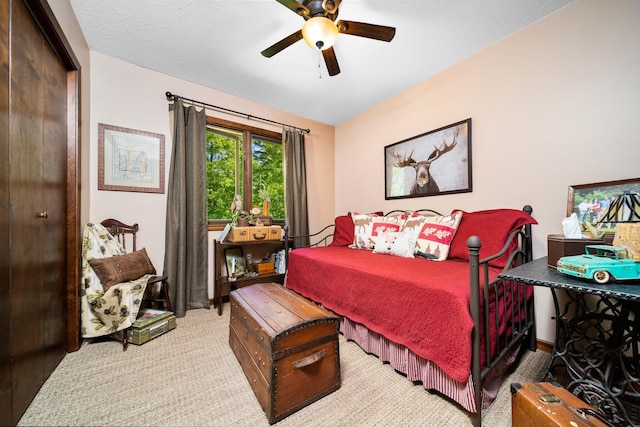 bedroom with light carpet, a textured ceiling, and ceiling fan