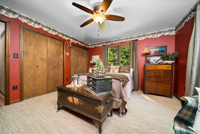 bedroom featuring light carpet, a textured ceiling, and ceiling fan