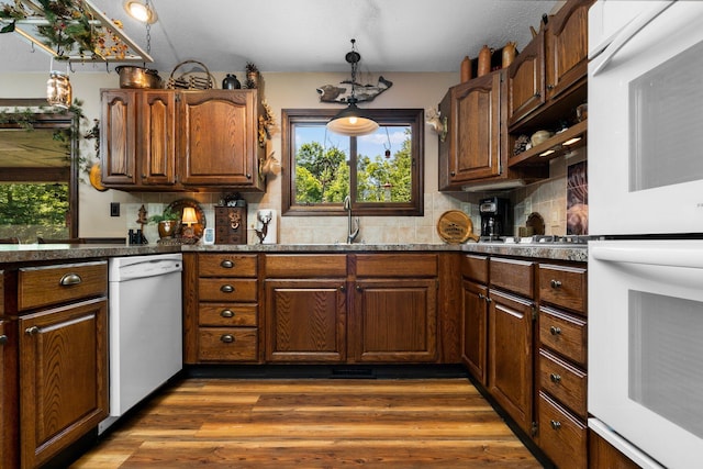 kitchen featuring tasteful backsplash, white appliances, sink, dark hardwood / wood-style floors, and hanging light fixtures