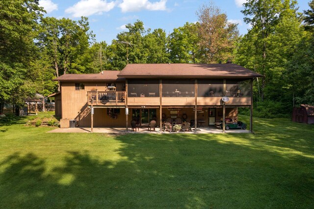 rear view of property featuring a patio area, a sunroom, a yard, and a deck