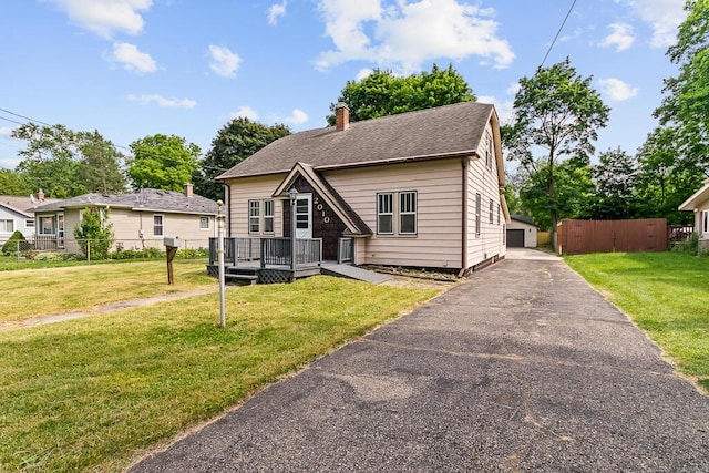 bungalow-style home with a garage, an outbuilding, a wooden deck, and a front yard