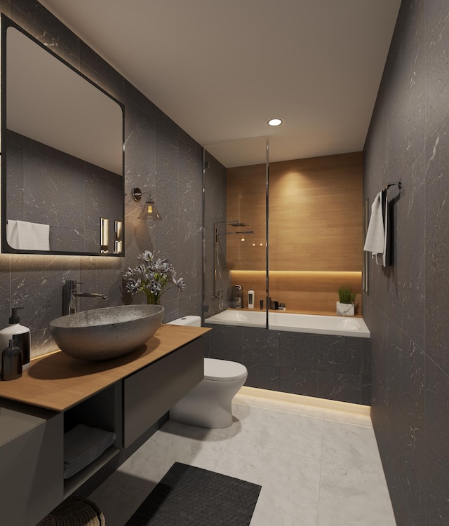 bathroom featuring toilet, tile patterned flooring, vanity, tile walls, and a bath