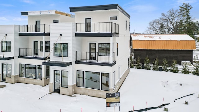 snow covered back of property featuring a balcony