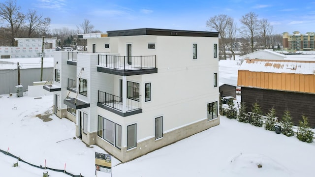 snow covered back of property featuring a balcony