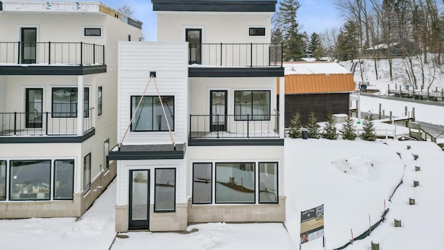 snow covered back of property with a balcony