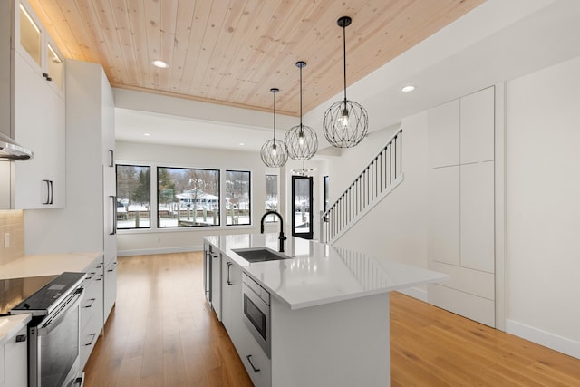 kitchen featuring a kitchen island with sink, sink, pendant lighting, and white cabinetry