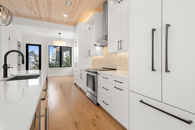 kitchen with pendant lighting, sink, white cabinets, decorative backsplash, and stainless steel electric stove