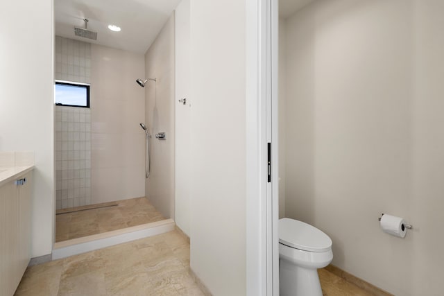 bathroom featuring vanity, tiled shower, and toilet