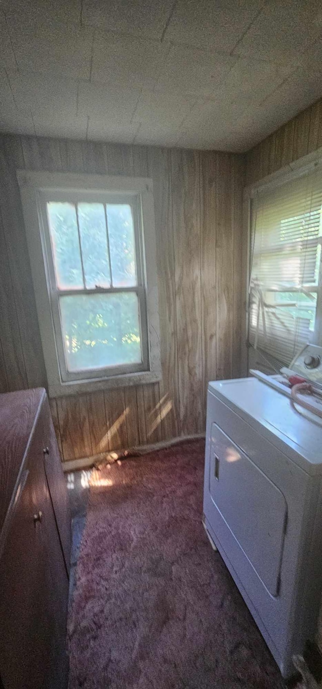 interior space with wooden walls, washer / clothes dryer, and dark colored carpet