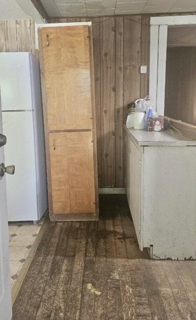 kitchen featuring wood walls, white fridge, and dark hardwood / wood-style flooring