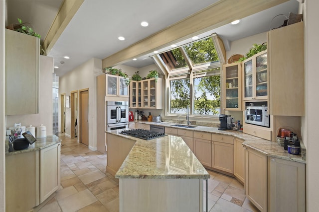 kitchen with light brown cabinetry, sink, light stone counters, black gas stovetop, and stainless steel double oven