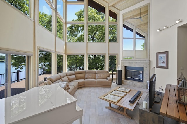 living room featuring plenty of natural light, a high end fireplace, wood-type flooring, and a high ceiling