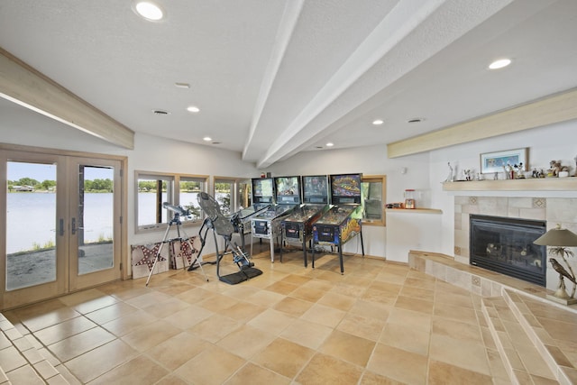 exercise room featuring a fireplace, light tile patterned floors, a water view, a textured ceiling, and french doors