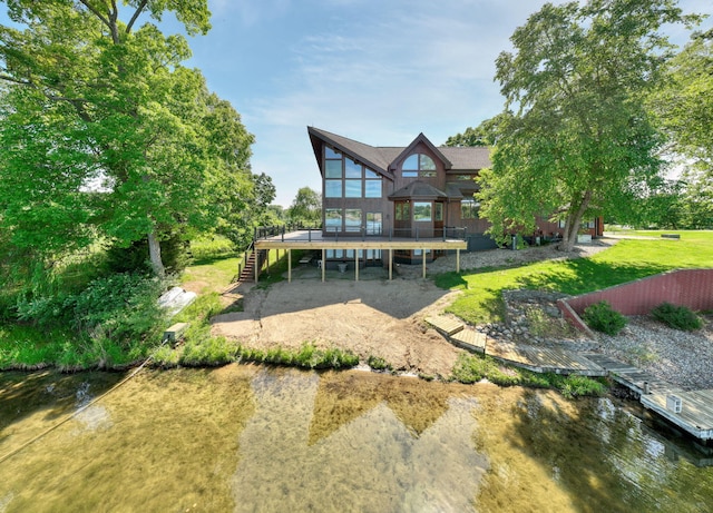 back of property with a deck with water view and a lawn