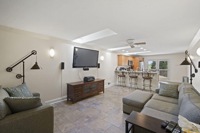 living room with ceiling fan and a skylight