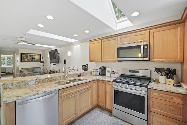 kitchen featuring sink, lofted ceiling with skylight, kitchen peninsula, and appliances with stainless steel finishes