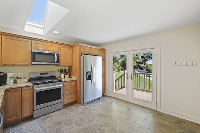 kitchen featuring french doors, a skylight, stainless steel appliances, and light stone countertops