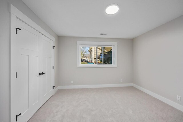 unfurnished bedroom featuring a closet and light carpet