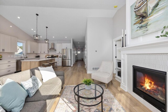 living room featuring high vaulted ceiling and light hardwood / wood-style floors