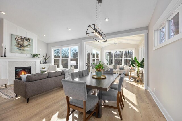 dining area featuring vaulted ceiling, a fireplace, and light hardwood / wood-style flooring