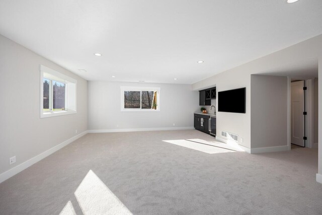 unfurnished living room featuring light colored carpet and indoor bar