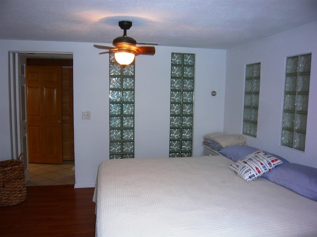 bedroom featuring hardwood / wood-style flooring, ceiling fan, and a textured ceiling