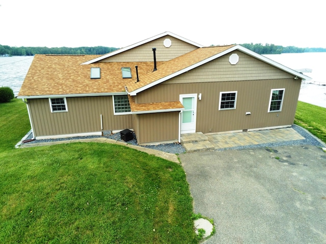 back of property with a water view and a yard