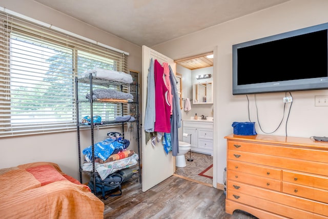 bedroom featuring hardwood / wood-style floors, ensuite bath, and sink