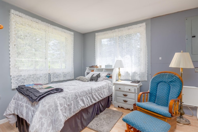 bedroom with electric panel and light hardwood / wood-style floors