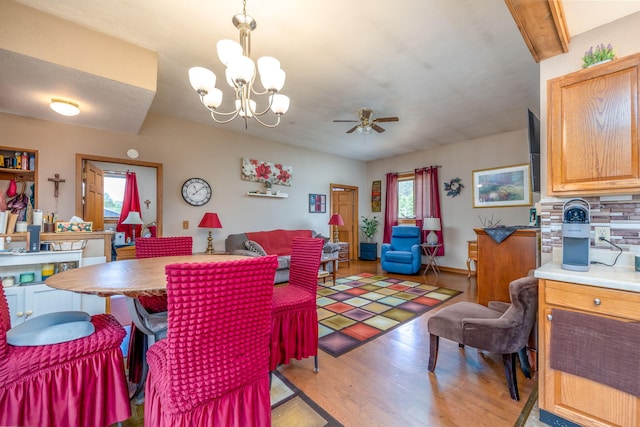 dining area featuring beam ceiling, ceiling fan with notable chandelier, and light hardwood / wood-style floors