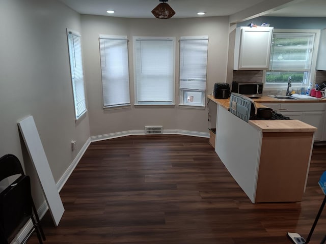 kitchen with white cabinetry, butcher block countertops, dark hardwood / wood-style floors, and sink