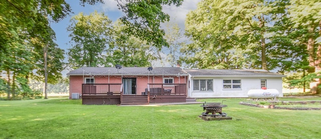 rear view of house with a wooden deck, a fire pit, and a lawn