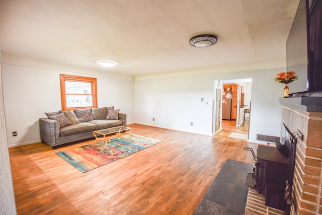 living room with a wood stove, hardwood / wood-style floors, and a fireplace