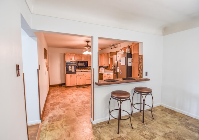 kitchen with black appliances, a breakfast bar area, backsplash, ceiling fan, and kitchen peninsula