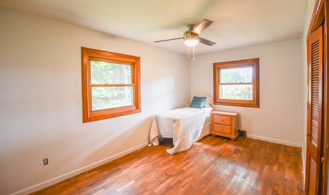 bedroom with multiple windows, dark hardwood / wood-style floors, a closet, and ceiling fan