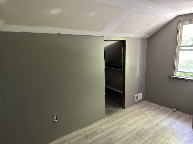 spare room featuring wood-type flooring and vaulted ceiling