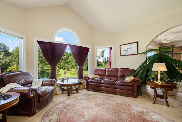 living room with ceiling fan, light colored carpet, high vaulted ceiling, and a wealth of natural light