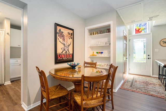 dining area featuring built in shelves and dark hardwood / wood-style floors