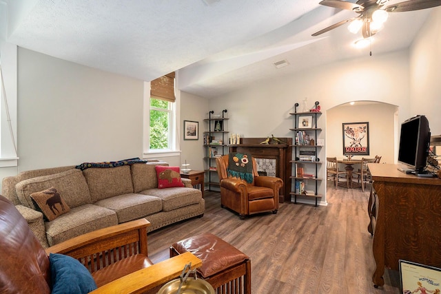 living room featuring lofted ceiling, hardwood / wood-style floors, a textured ceiling, and ceiling fan