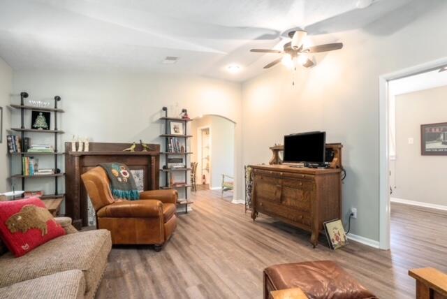 living room featuring lofted ceiling, wood-type flooring, and ceiling fan