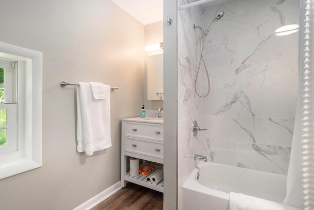 bathroom with wood-type flooring, a healthy amount of sunlight, vanity, and washtub / shower combination