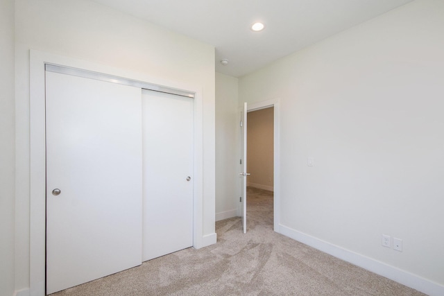 unfurnished bedroom with light colored carpet and a closet