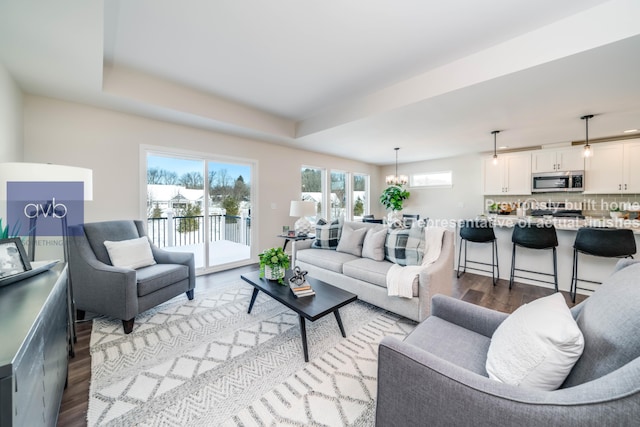 living room with a chandelier, light hardwood / wood-style flooring, and a raised ceiling