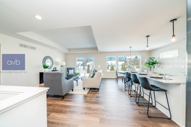 living room featuring hardwood / wood-style floors, a notable chandelier, and a tray ceiling