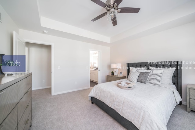 carpeted bedroom featuring ceiling fan, a raised ceiling, and ensuite bath