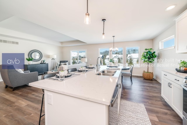 kitchen featuring sink, a center island with sink, a kitchen breakfast bar, and hanging light fixtures