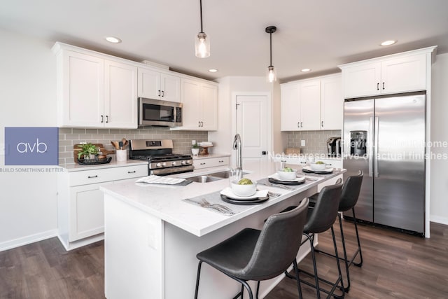 kitchen with an island with sink, white cabinetry, hanging light fixtures, and stainless steel appliances