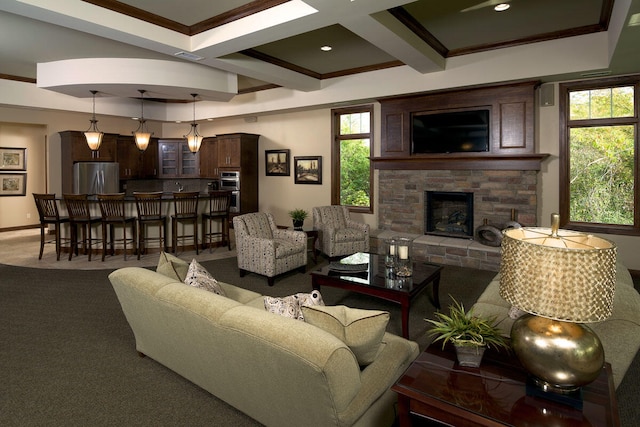 carpeted living room with crown molding, coffered ceiling, beamed ceiling, and a stone fireplace